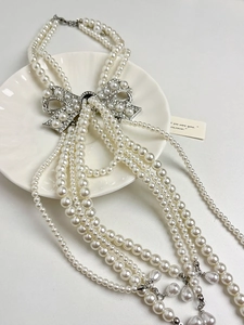 Detail of multi-layer pearl bridal necklace with a crystal bow brooch and teardrop pendant