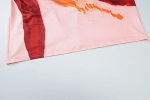 Detailed close-up of pink knit fabric with abstract ink print and double-needle hem stitching
