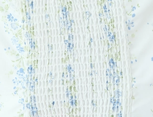 Detail of smocking elastic fabric with blue and green floral pattern on white top