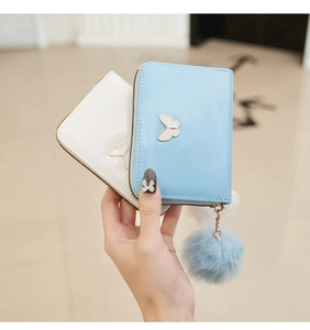Detail of light blue and white leather purses with butterfly ornaments and fur pompom