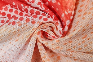 Detail of red and orange gradient polka dot mesh fabric with soft pleats and texture