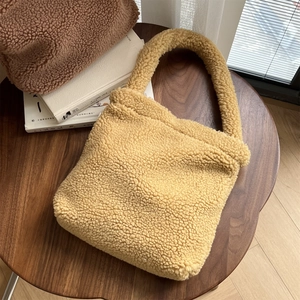 Detailed close-up of soft mustard yellow shearling faux fur tote bag on wooden table