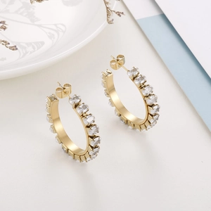 Detail shot of golden hoop earrings with oval cut cubic zirconia and metal plating