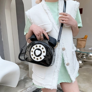 Detail of creative vintage black patent leather telephone crossbody bag with heart dial