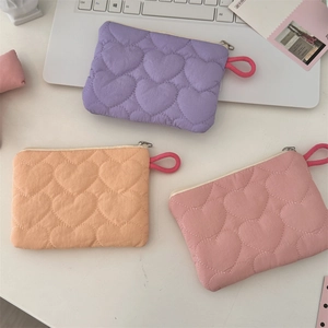Macro detail of heart-quilted texture and zipper puller on candy-colored mini pouches