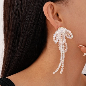 Detail shot of shimmering glass crystal bow earrings with elegant dangling beaded tassels