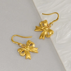 Élégantes boucles d'oreilles nœuds dorés avec cristaux sur une surface texturée