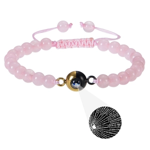 Detailed macro view of 100 languages I Love You projection stone on pink beaded bracelet