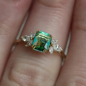 Elegant gold ring with rectangular green emerald stone and marquise zircon accents