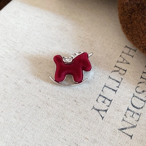 Close-up of a red flocked rocking horse brooch with crystal rhinestones on metal base