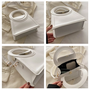 Detail view of white trapezoid handbag showing gold hardware, stitching and interior space