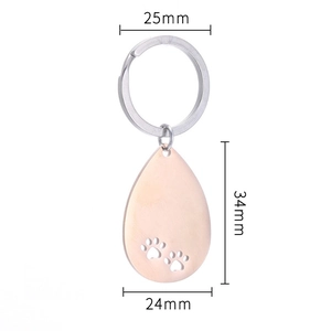 Macro detail of rose gold teardrop keychain with paw cutouts and size measurements