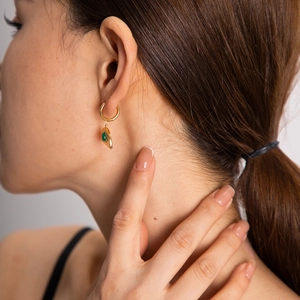 Close-up of 18k gold plated round earrings featuring an elegant green gemstone drop