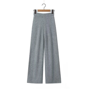Detail of grey knitted wide-leg trousers with vertical rib texture on a wooden hanger