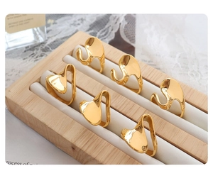 Detail of minimalist gold wavy rings with a liquid metal texture on a jewelry display