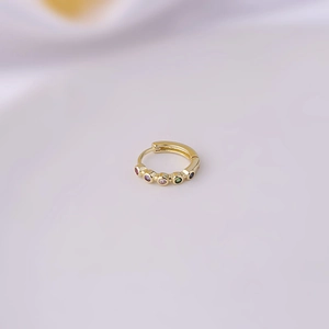 Macro view of gold-plated copper hoop earring with inlaid colorful zircon stones