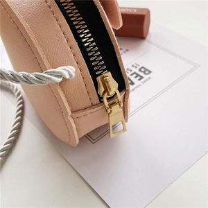 Dettaglio della mini borsa tonda rosa con cerniera in metallo dorato e tracolla in corda