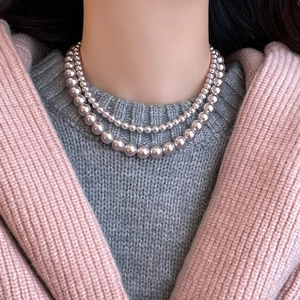 Close-up of elegant double-layered lavender pearl necklace styled on a soft knit sweater