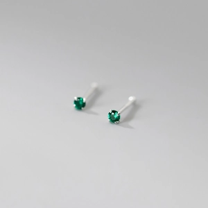 Macro shot of a four-prong minimalist earring with a brilliant round-cut green gemstone