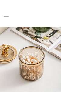 Macro view of a luxury striped glass storage jar with a gold bear lid and cotton swabs
