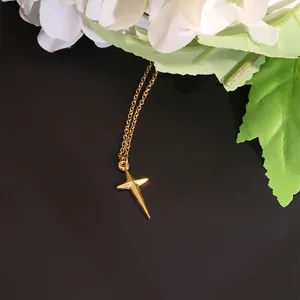 Minimalist 18K gold star cross pendant necklace with fine chain on a dark surface