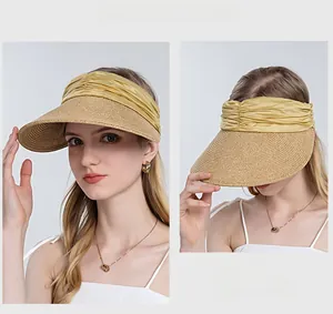 Detail of summer straw sun visor with golden pleated silk trim and wide woven brim