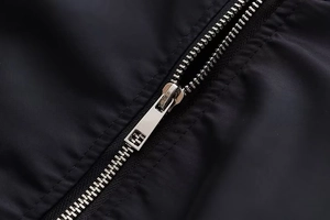 Detailaufnahme eines silbernen Metallreißverschlusses an einer schwarzen Bomberjacke