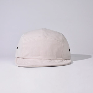Close-up of beige 5-panel camper hat showing canvas texture and side metal eyelets