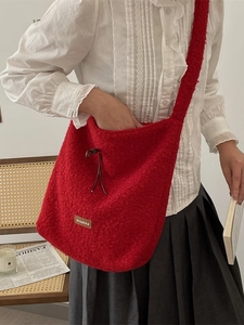 Soft plush red crossbody bag with drawstring closure and large capacity displayed on model