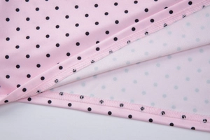 Detail of pink fabric with black polka dots showing quality stitching and hem texture