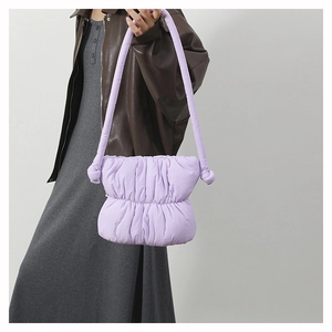 Detail of light purple quilted puffer bag featuring a unique large knotted shoulder strap