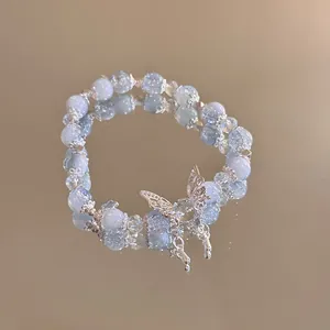 Detailed close-up of beaded butterfly bracelet with blue stones on golden mirror base