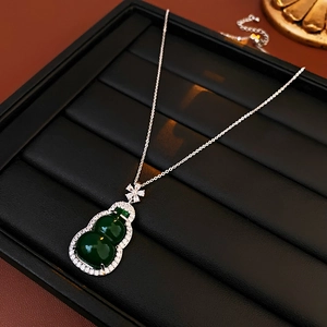 Detail of green zircon gourd pendant necklace on black leather display tray