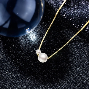 Exquisite gold box chain necklace featuring two elegant white faux pearls on black surface