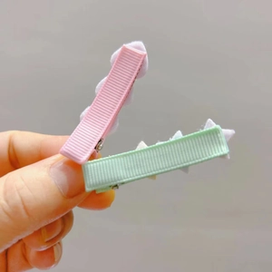 Macro shot of pink and light green glitter hair clips with ribbed ribbon and cotton stars