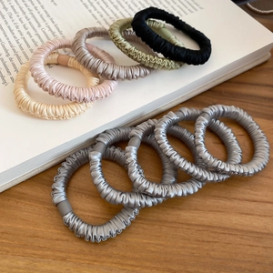 Detailed view of satin scrunchies with pleated texture on a book and wooden desk