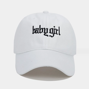 Dettaglio del ricamo baby girl in stile gotico su un berretto di cotone bianco