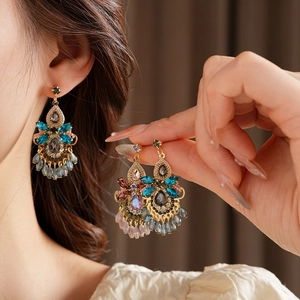 Detailed close-up of bohemian gold earrings with colorful crystals and teardrop beads