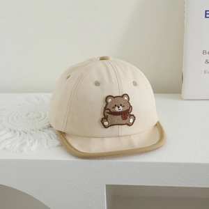 Detail shot of a beige baby baseball cap featuring a cute brown bear embroidery