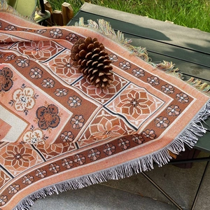 Close-up of bohemian woven camping blanket with floral patterns and colorful tassels