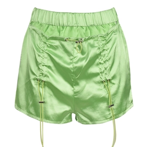 Detail view of bright green satin shorts with adjustable drawstrings and metallic tips