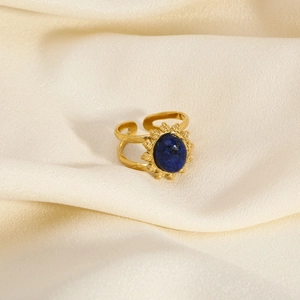 Detail of adjustable gold ring featuring a blue oval stone and sunburst-style setting
