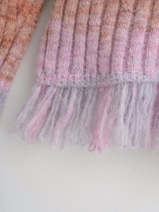 Detail of pink-orange gradient knit fabric featuring ribbed texture and long fringes