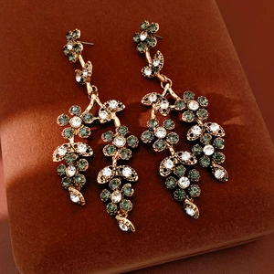 Macro shot of vintage gold flower drop earrings with rhinestones on velvet
