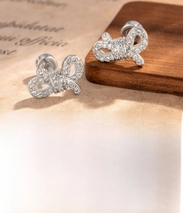 Details von silbernen Schleifenohrringen mit Zirkon-Pavé, Titanstahl und Kupfermaterial