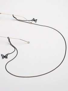 Détail d'une chaîne de lunettes noire avec pendentifs papillon en strass sur lien métallique