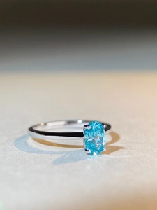 Macro shot of oval blue gemstone ring showing intricate facets and silver claw setting