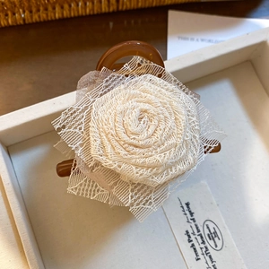 Dettaglio della grande molletta per capelli con rosa in pizzo su un vassoio espositivo