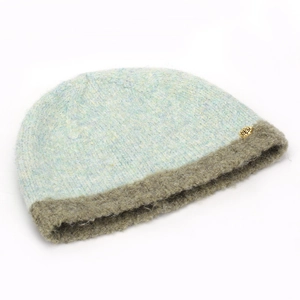 Detailed texture of dual-tone knit beanie with plush brim and gold rose badge