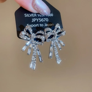 Macro view of S925 silver bow earrings with sparkling cubic zirconia and tassels